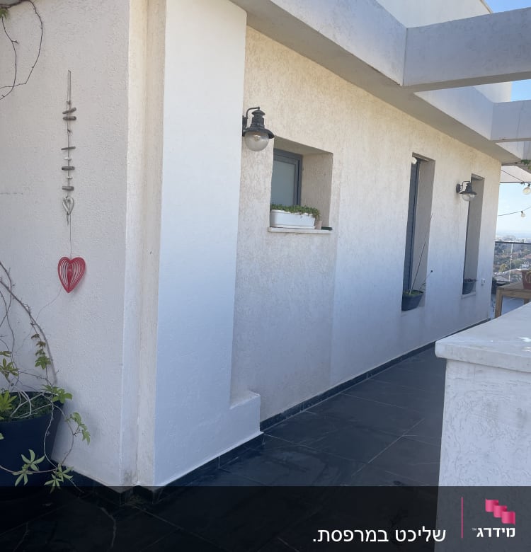 מרפסת עם קיר לבן, עציצים וקישוט תלוי